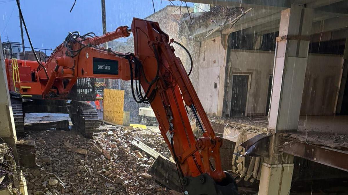 A view from inside the M&S unit shows the machinery knocking down the wall and surrounded by pulversised brick and concrete.