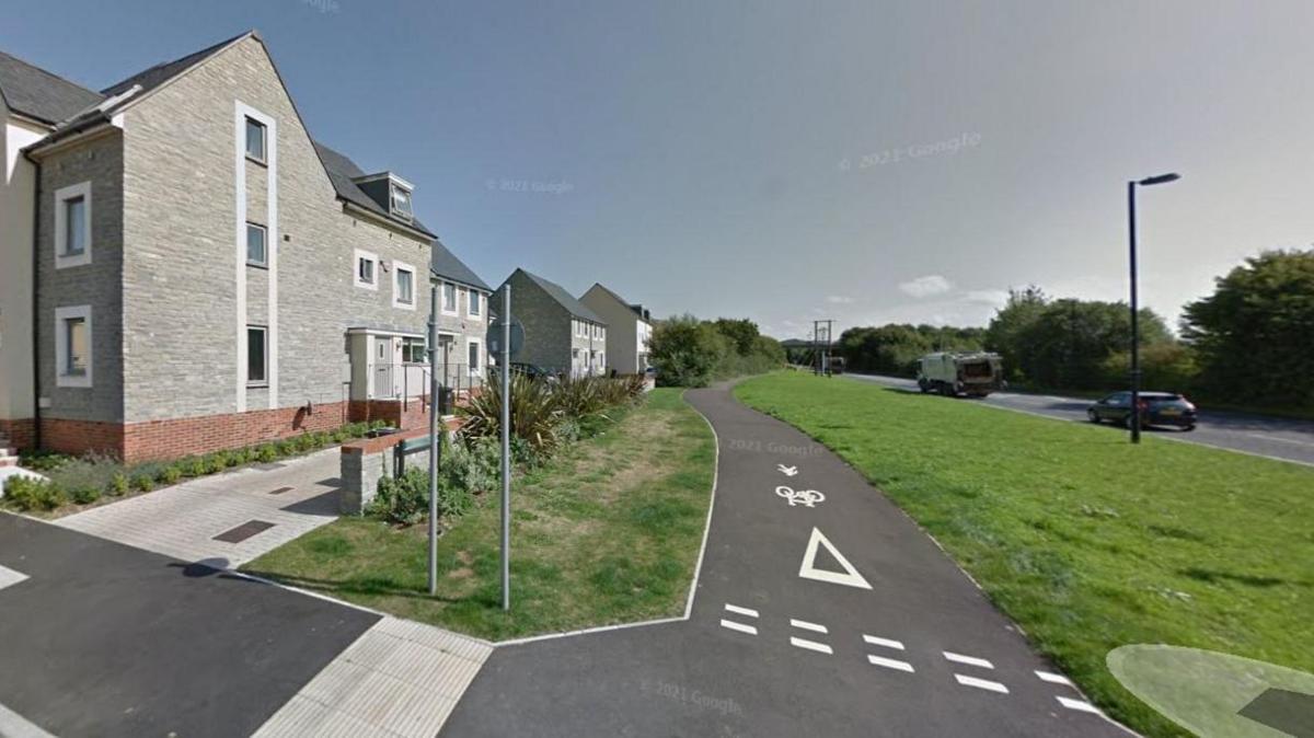 Part of the Strawberry Line route on the eastern edge of Wells with a tarmac cycle path next to a road on one side and houses on the other.