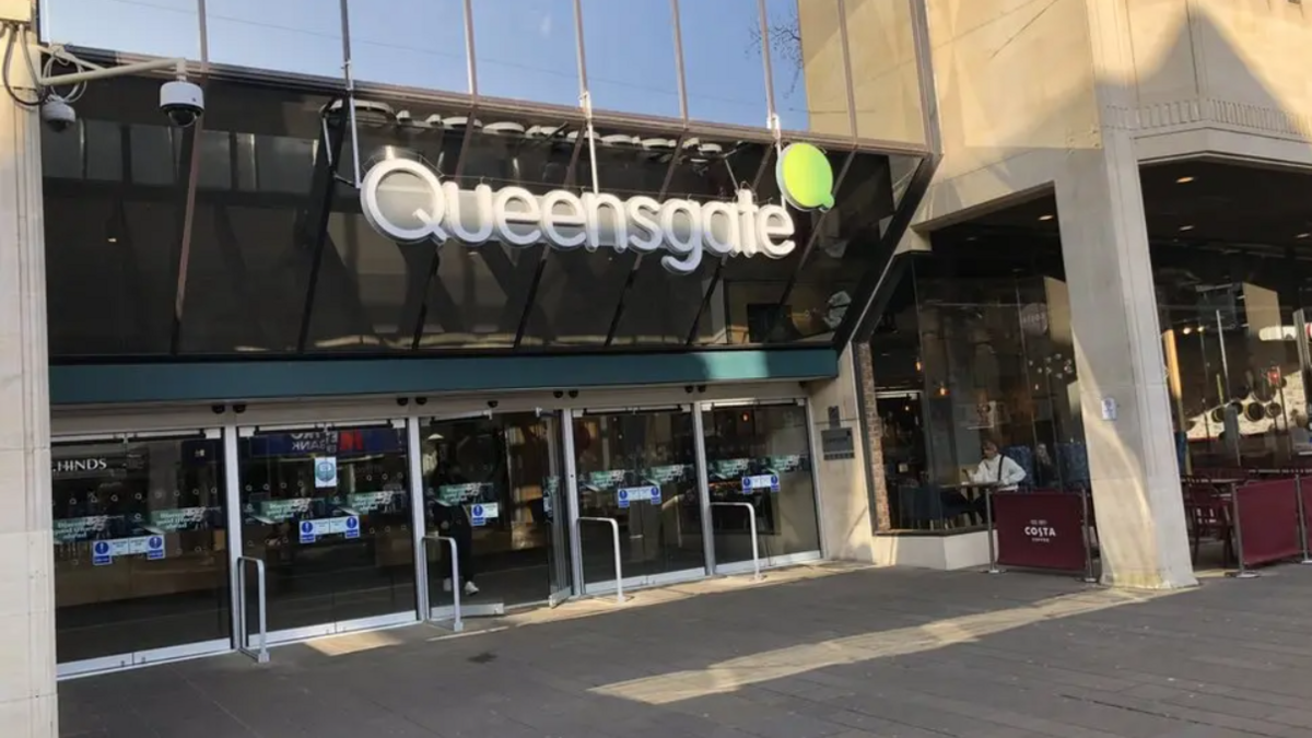 Front of Queensgate shopping centre, with a sign written in white, next to a Costa coffee shop