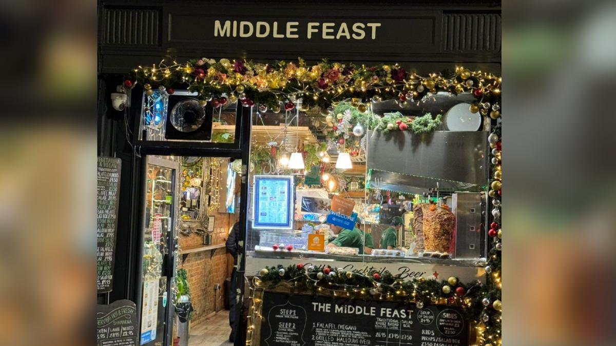 The front window of the Middle Feast restaurant with christmas lights and garlands with baubles. 