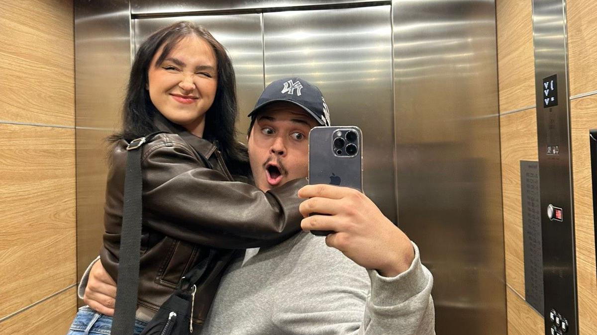 A man and woman hug while taking a selfie in a lift mirror