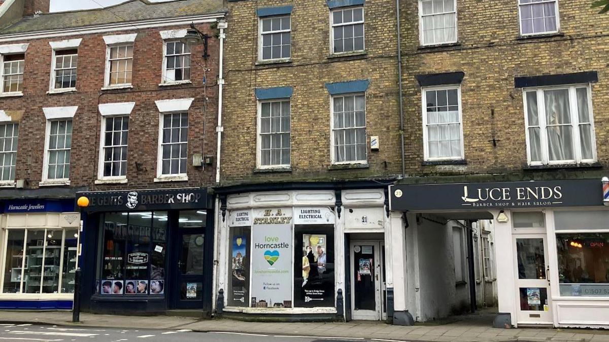 A view of Horncastle Conservation Area showing four shops, including two barber's shops and an abandoned "Love Horncastle" shop