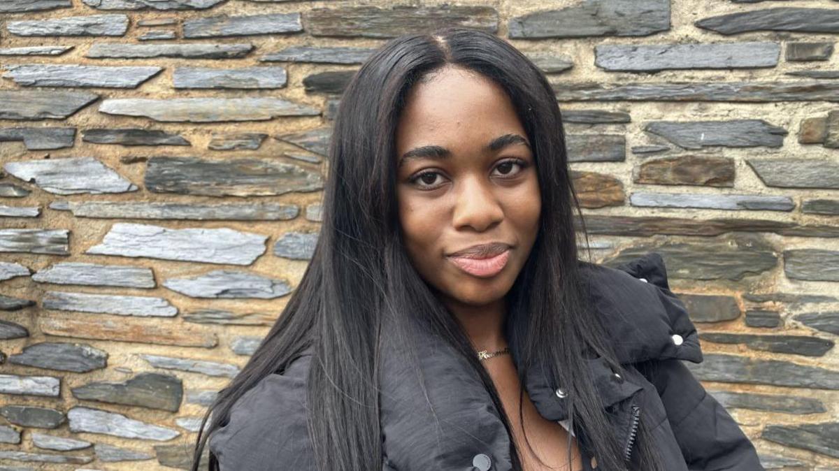 Henrietta Bongu, a woman with long dark hair and wearing a black jacket.