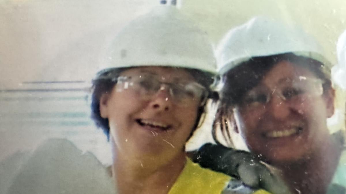 Marie and Ros wearing high-visibility jackets and white helmets ina n old photograph