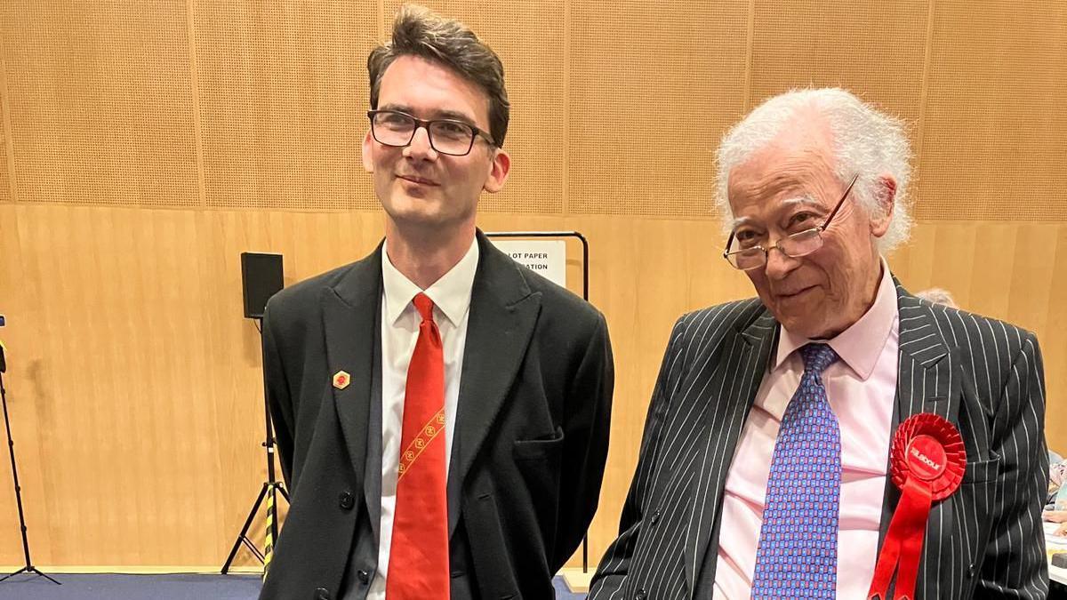 A young man and older man stand next to each other