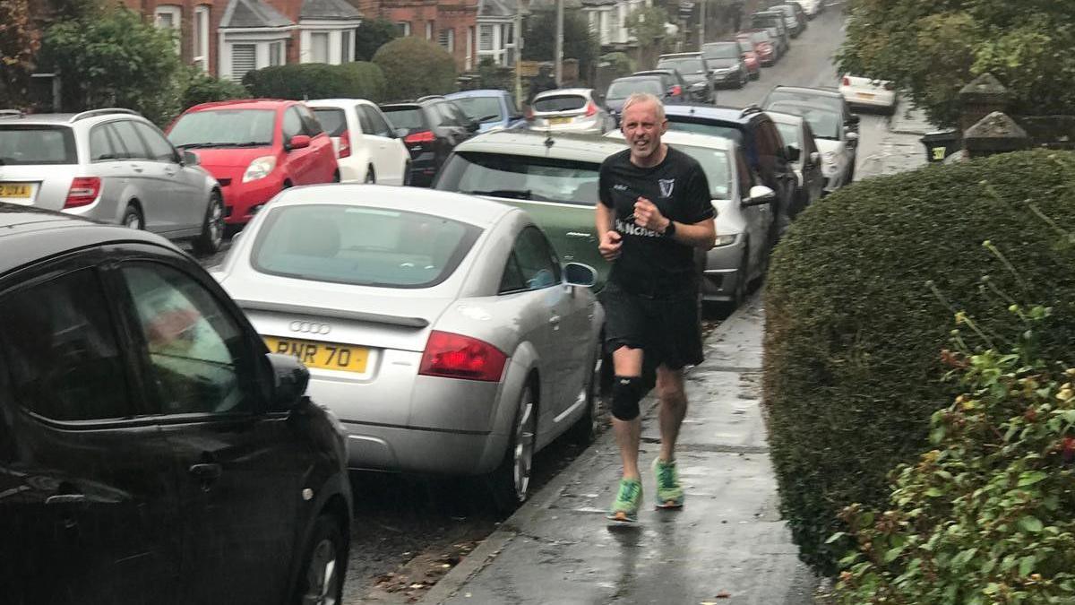 Stephen Griffin running on the pavement in shorts and t-shirt.