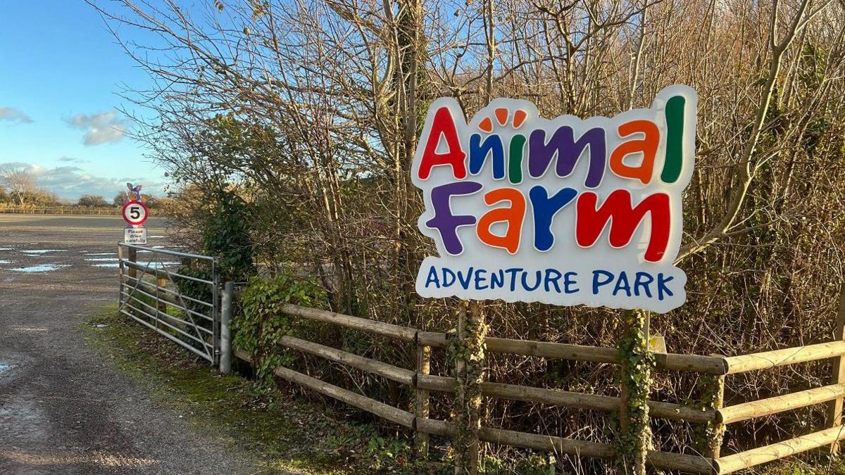 A brightly coloured sign outside of the farm which reads "Animal Farm Adventure Park."