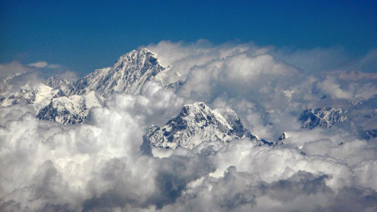 An aerial view image of Mount Everest with Mount Ama Dablam. Clouds surround the snow-capped mountains. 