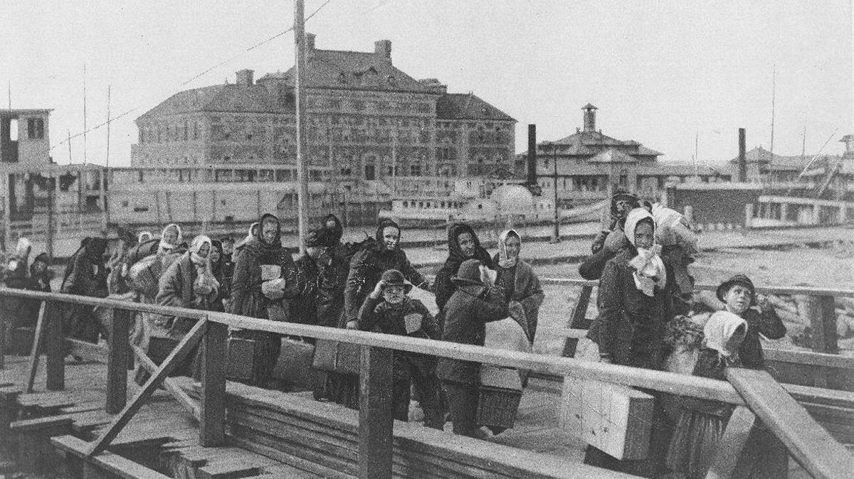 Black and white photograph of mostly women and children, many of whom came from Eastern Europe. They are clutching their suitcases and belongings