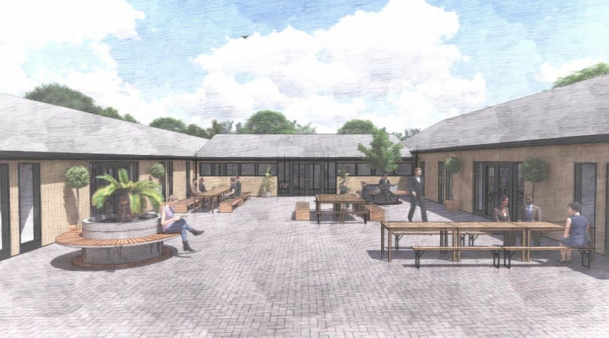 The courtyard has grey cobbles, benches and some plants.