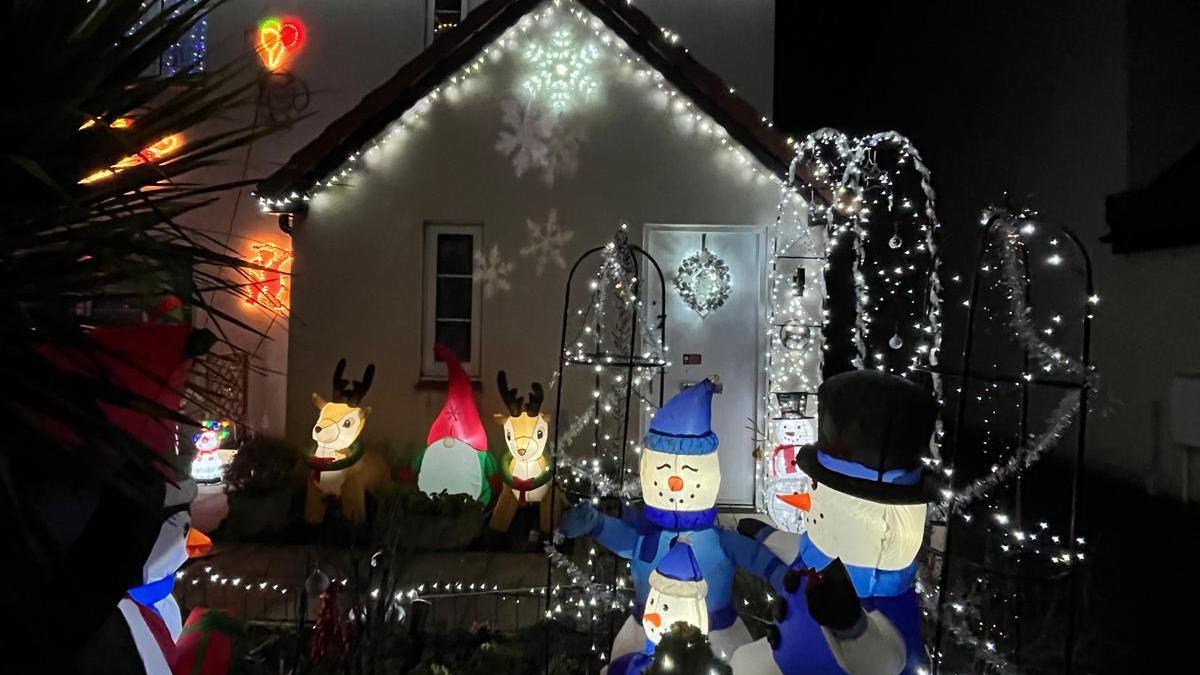 A Christmas lights display and scene outside someone's home