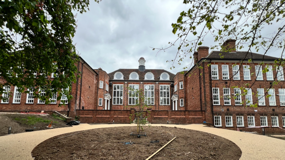 Large Victorian orange brick building with large rectangular white framed windows offset by courtyard