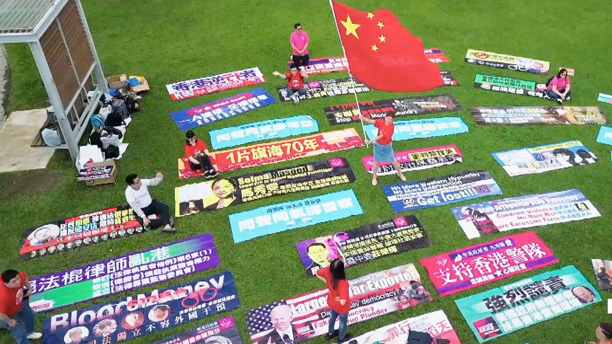 A woman waves a Chinese flag, surrounded by huge brightly coloured banners