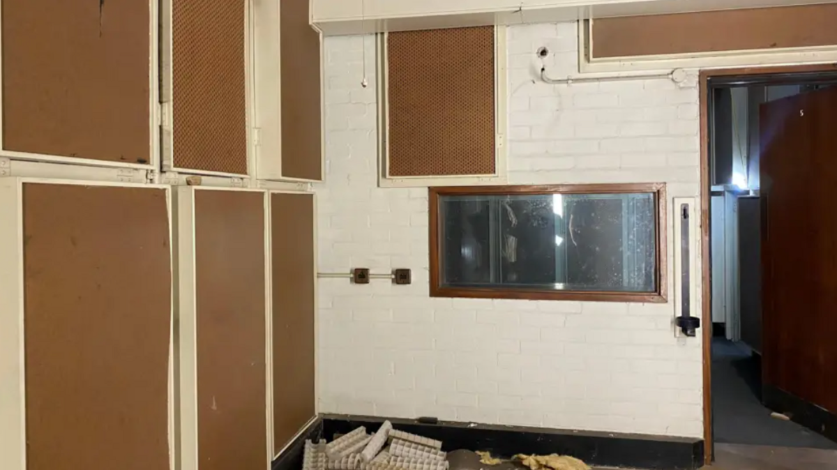 An image of a former BBC broadcasting studio inside Nottingham War Rooms, which shows white walls and a clear window into a studio
