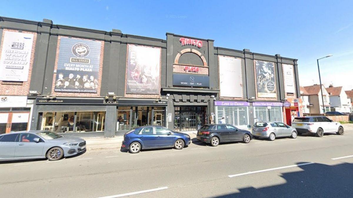 The Rialto Plaza sign on the outside of the Moseley Avenue building is red and features a semi circle brick work design. It appears to be quite a big venue above several shops including a dance studio. There are posters of Elvis Presley and George Michael tribute nights.