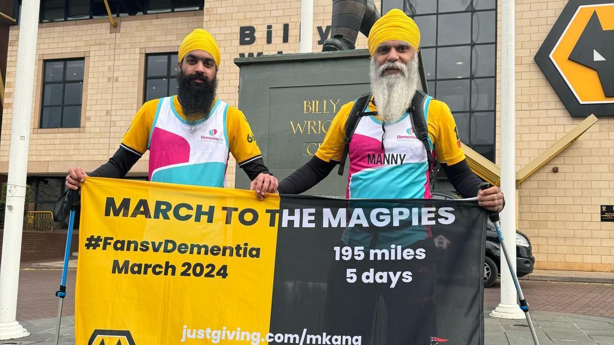 Manny Singh Kang and his son Jeevan holding a banner