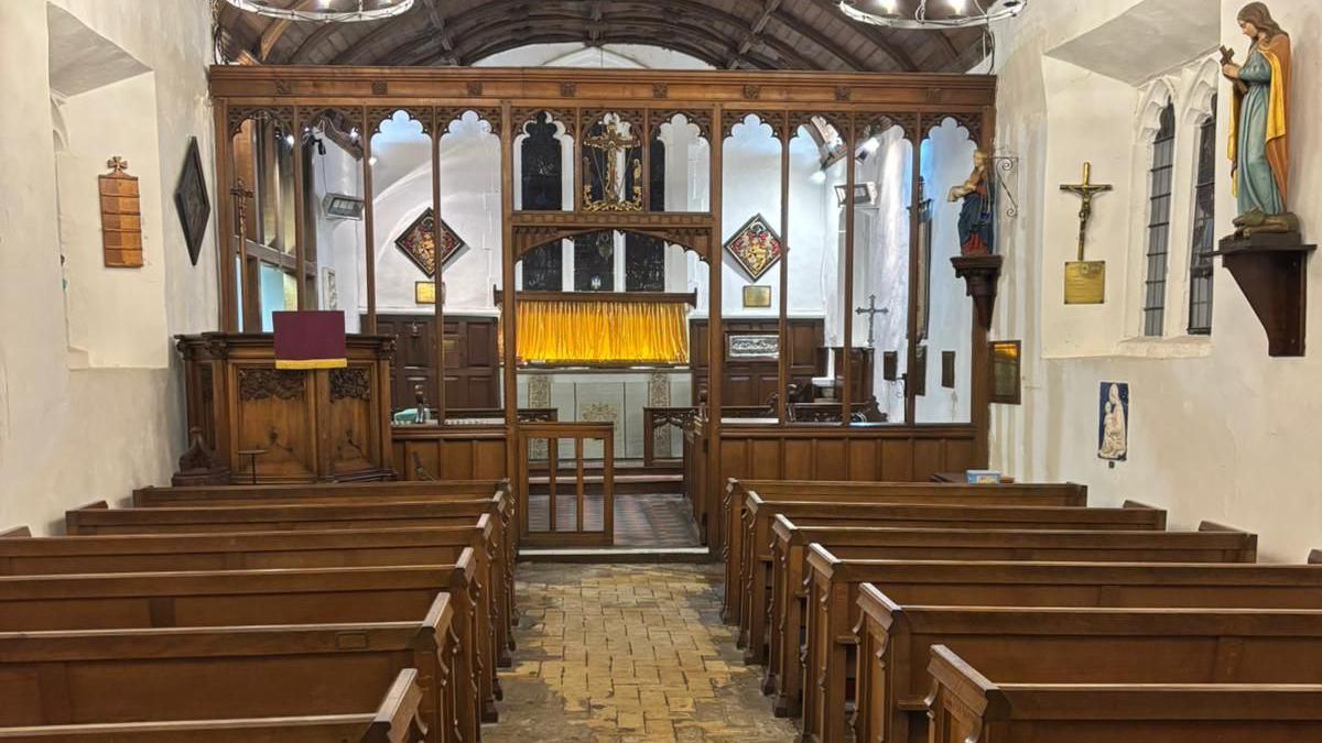 The inside of a church. There are rows of benches and an aisle in the middle.
There are images of Jesus and the cross on the walls