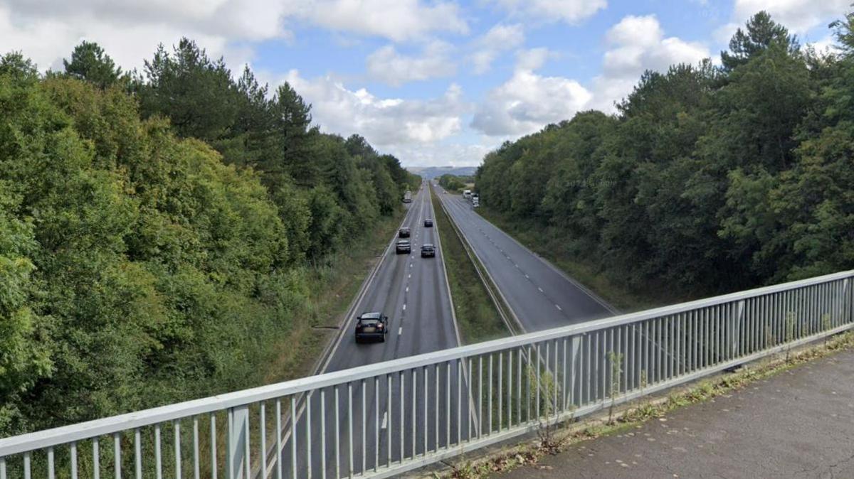 A Google maps screenshot of a section of the A40 road, taken from a bridge above. It is a long and straight dual carriageway with mature trees lining either side.