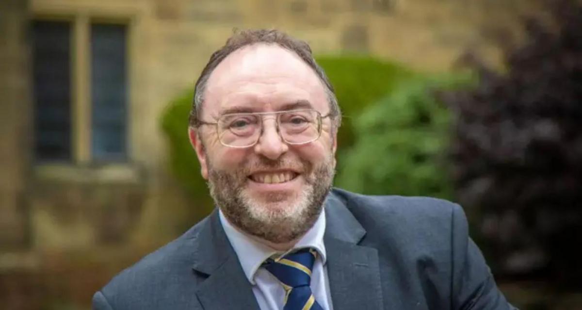 Man in a suit with glasses smiling at the camera