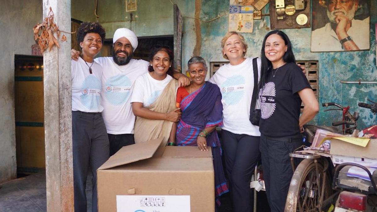 Six people smiling while standing behind a cardboard box