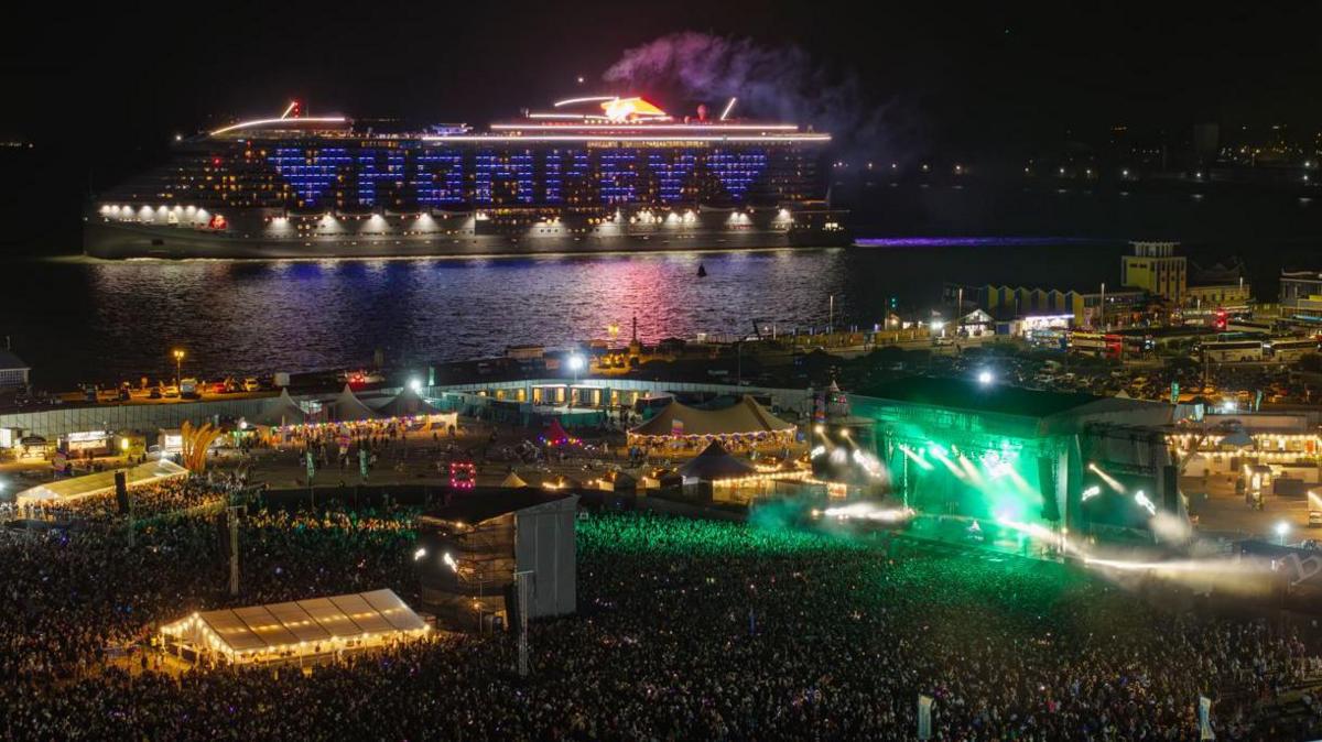 A cruise ship sets sail from Portsmouth on Friday evening to the backdrop of Fatboy Slim’s set. Its side is illuminated to spell "Pompey" with a heart 