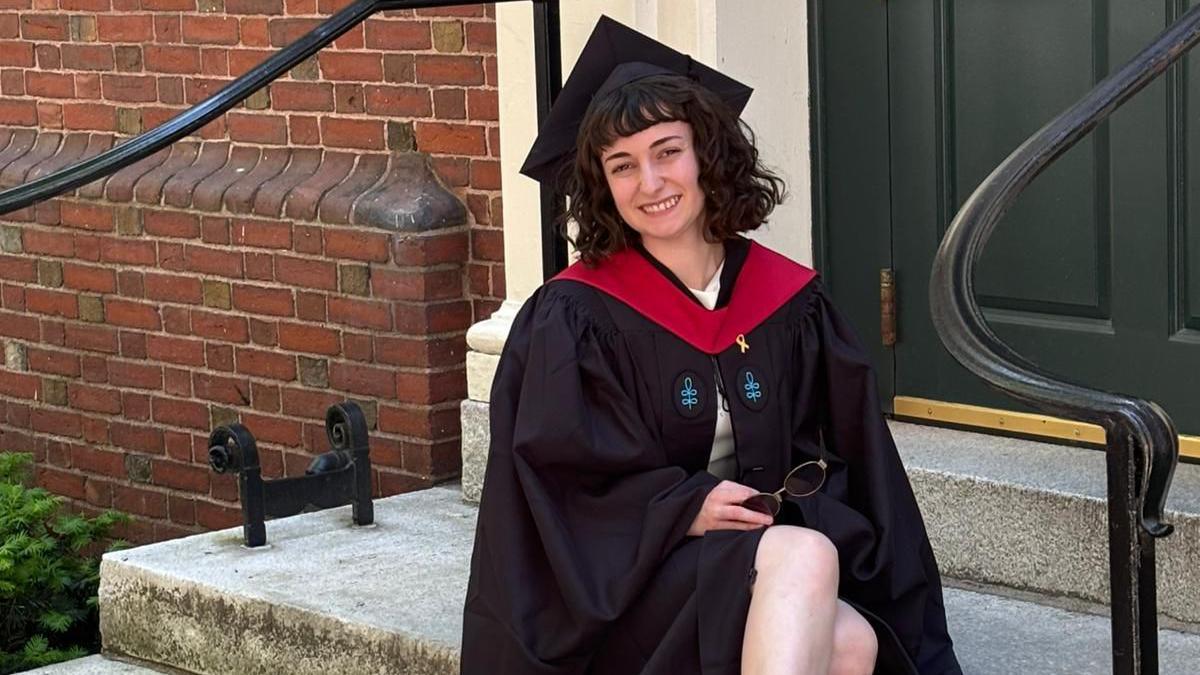 Nitsan Machlis wears a black graduation robe and black hat, pictured smiling