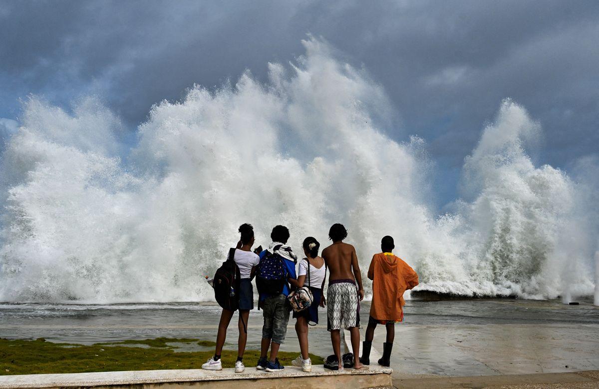  Young people look at waves crashing against the Malecon promenade in Havana due to the passage of Hurricane Milton on October 9, 2024