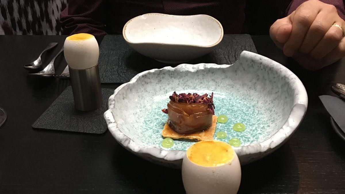 A dessert plate at Purnell's. It appears to be some kind of desert tasting dish, sitting in a grey/green sylised dish on a black table cloth, and a grey place mat and coaster. 