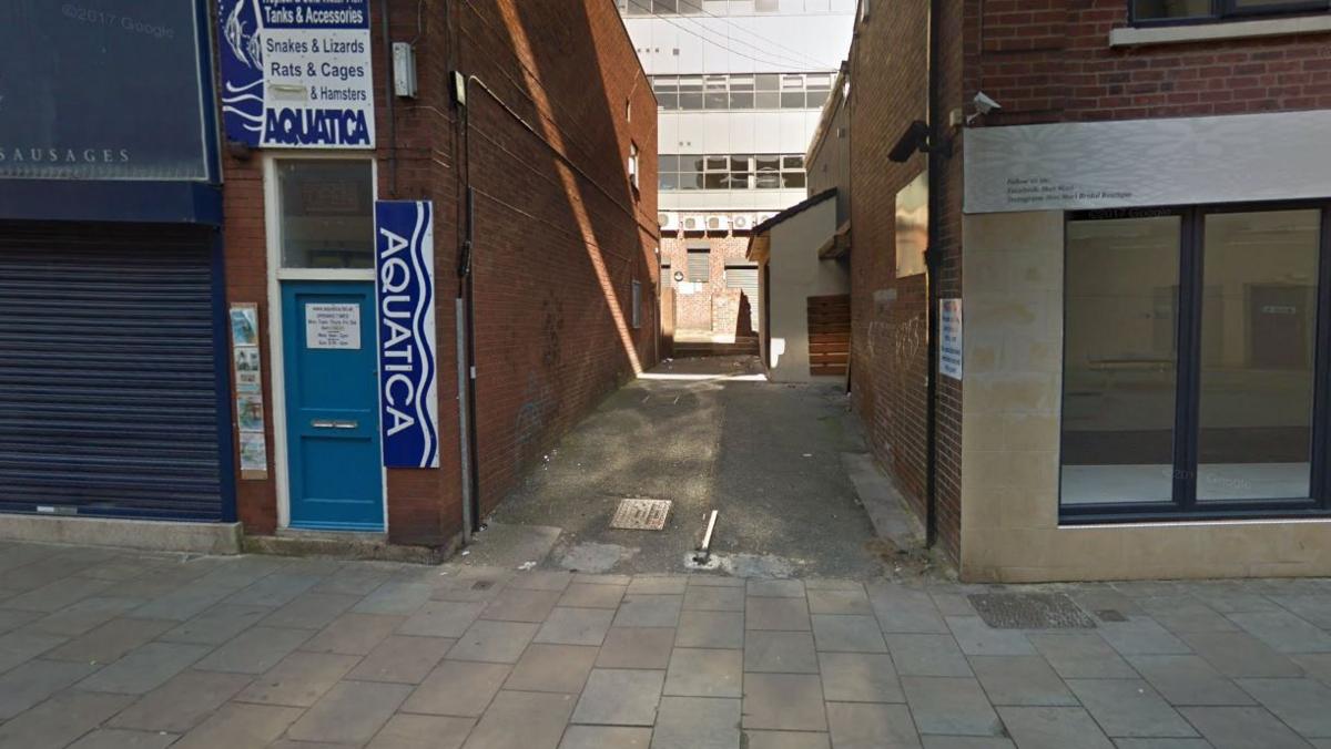 An alleyway between two buildings in Wakefield. The two buildings between the alleyway have red bricks. 