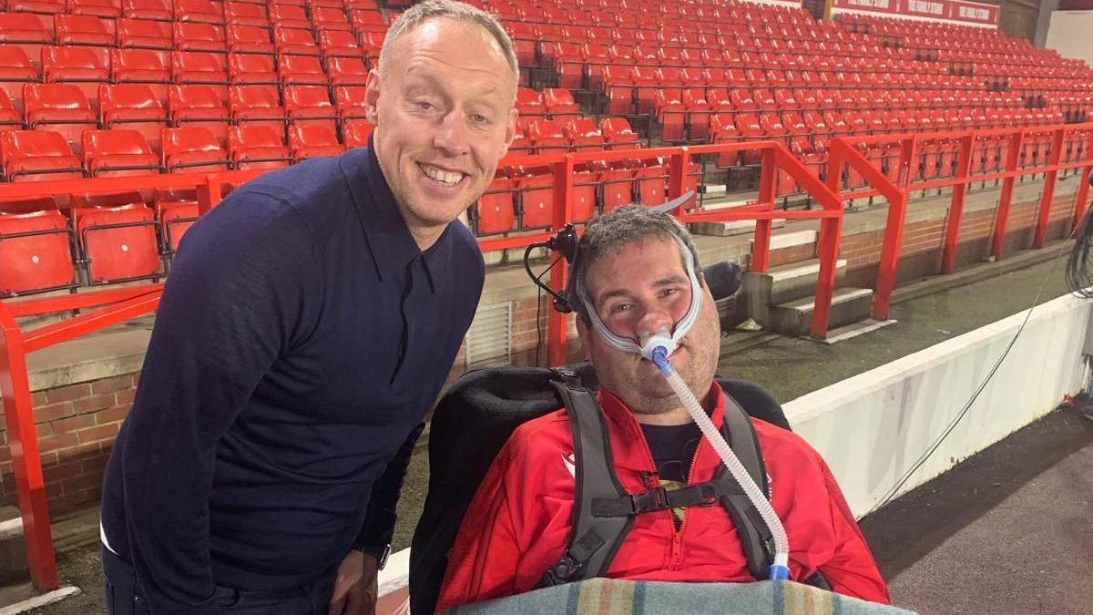 Sam Perkins, in a wheelchair, with former Nottingham Forest boss Steve Cooper, in front of seats at the club's ground