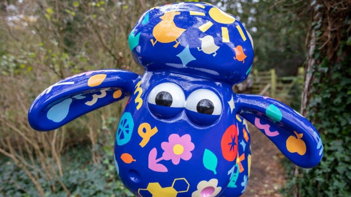 A model of animated character Shaun the Sheep is painted blue with brightly coloured flowers, birds and other decorations