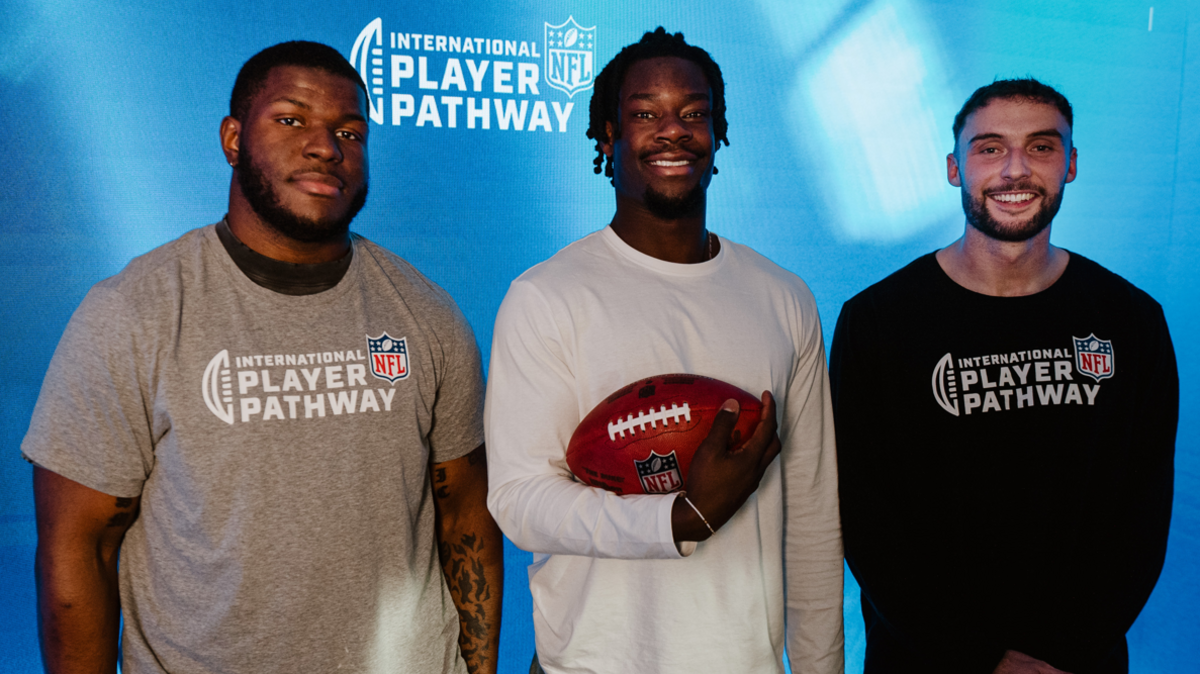 Dante Barnett, Mapalo Mwansa and Aaron Sexton posing in front of an NFL International Player Pathway sign