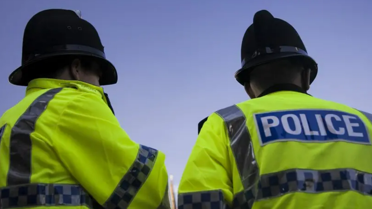 Two police officers facing away from the camera. They are wearing yellow high-vis jackets with the word: "POLICE" on them.