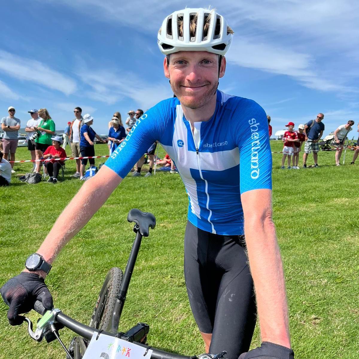 Man wearing a blue top, white helmet and holding a bike
