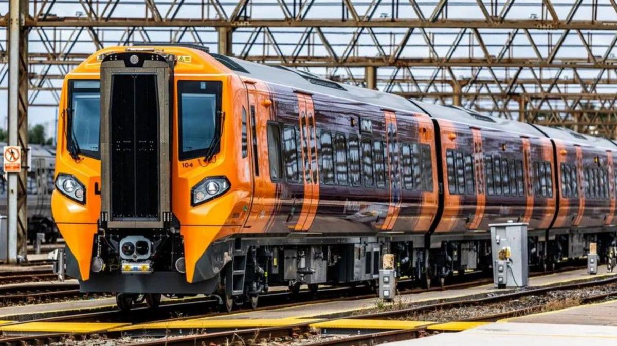 The outside of a West Midlands Railway train, which is painted orange and purple.