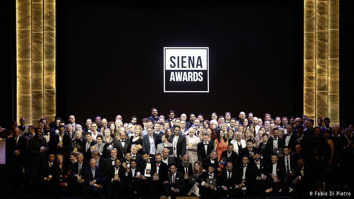 A group photo of all the photographers at the Siena Awards. Sme are kneeling down while others are standing up for the shot.