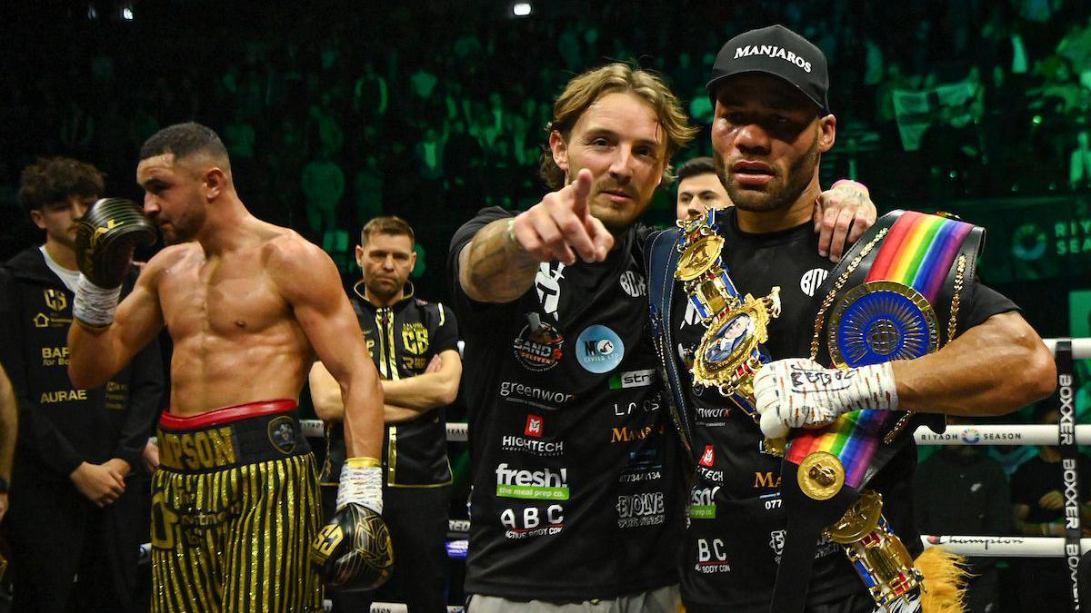 Troy Williamson celebrates with his titles with Callum Simpson in the background
