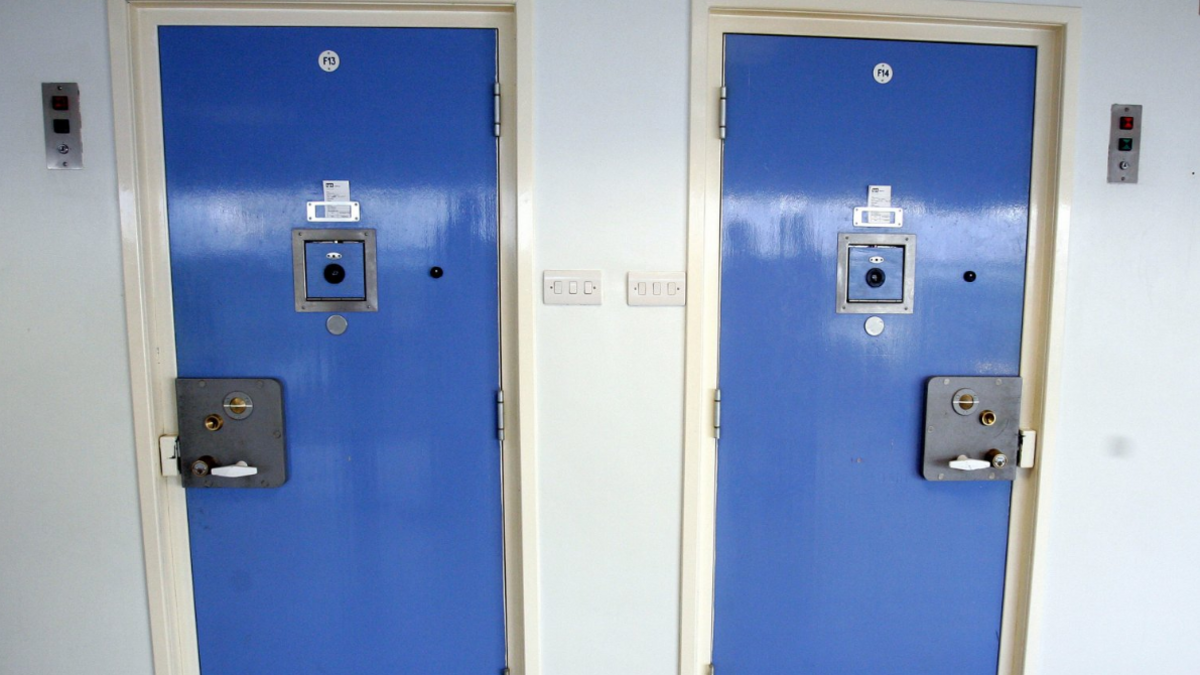 Shows two prison cells with blue doors and black locks. 