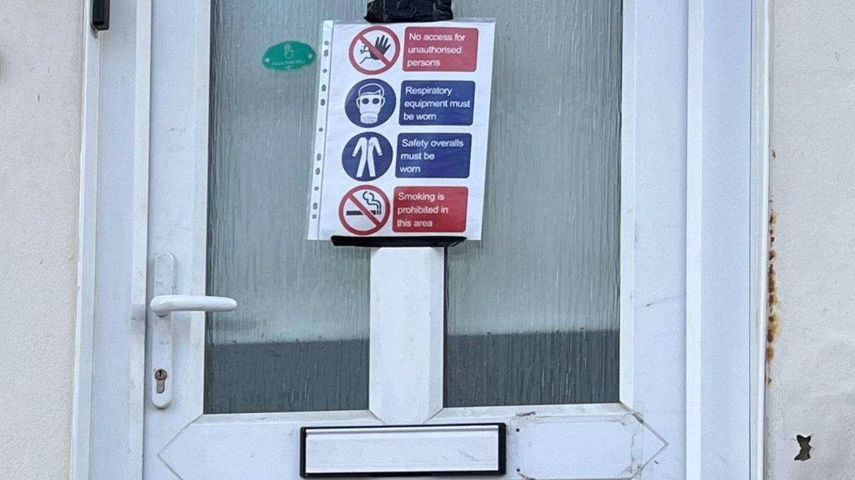 Mr Arnison's front door with a warning poster taped to it restricting access to "unauthorised persons"
