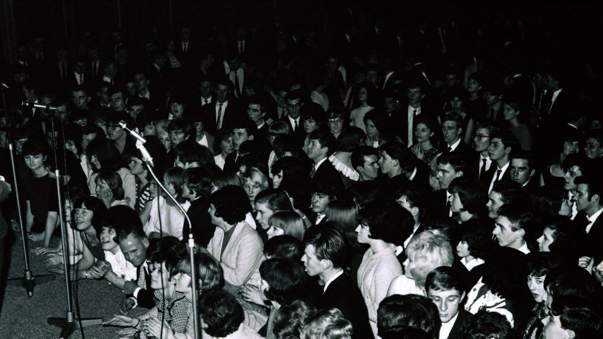 A black and white photo of fan pressed up against the stage at a gig in the gliderdrome