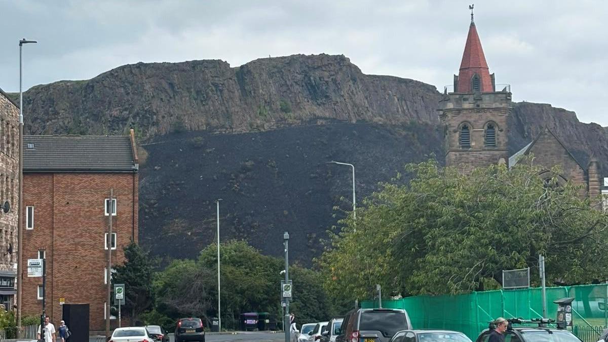 Arthur's Seat with burnt vegetation down its cliff face.