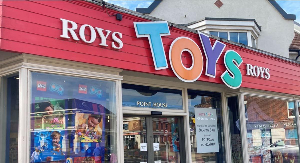 Roys Toys Shop with a sign that has red backing and toys in the shop windows.
