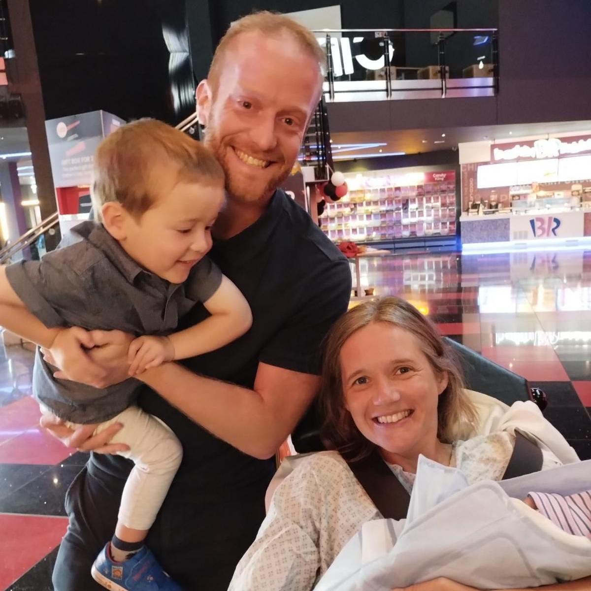 Sarah and Gareth smiling with their son and newborn daughter, shortly after she was born in Cineworld