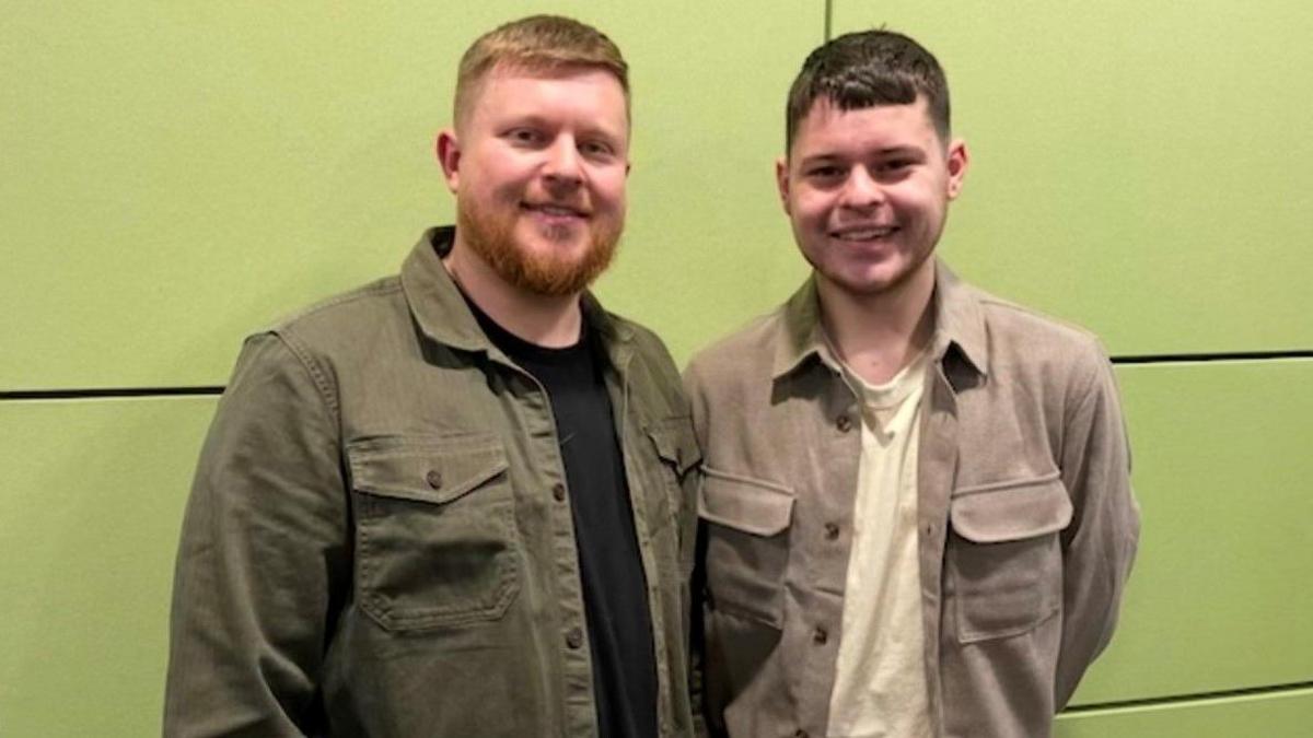 Brendon Manders (left), with brown hair, and Jaydon Manders, with darker hair, are smiling and looking at the camera. A green background is behind them.