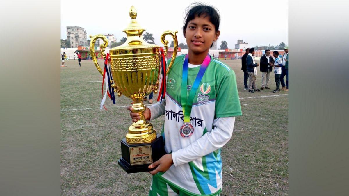 A young woman wearing a medal holds up a trophy