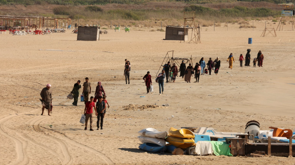 People carry their belongings across a beach as they leave Tyre - one of the southern Lebanon cities hit on Monday