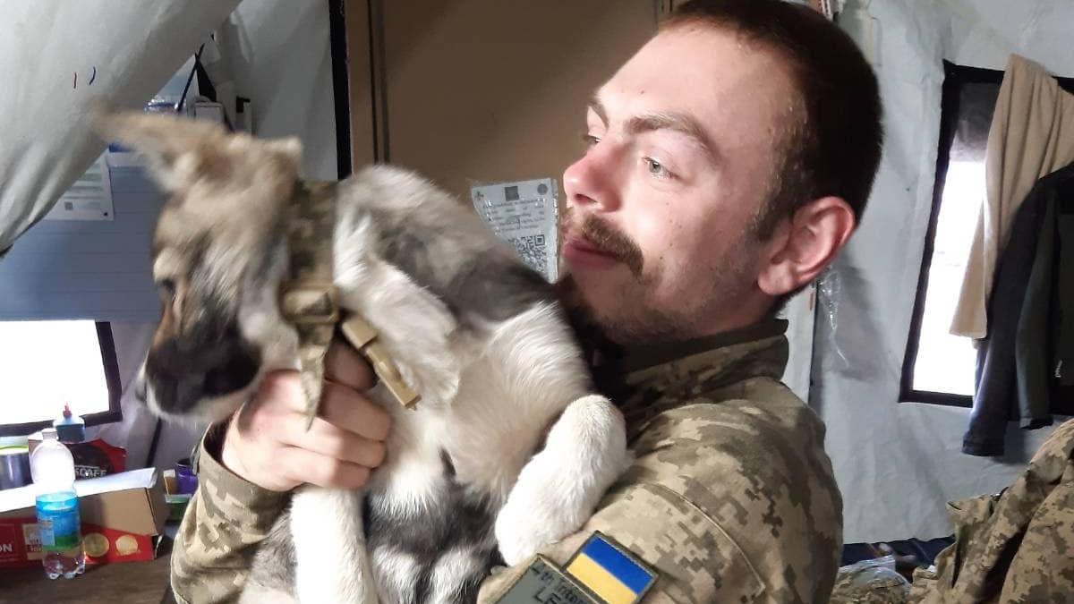 Callum Tindal-Draper in a makeshift army barracks holding a puppy while out in Ukraine.