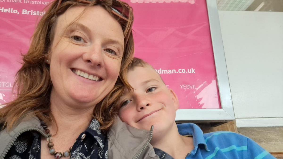 Elspeth Cordray with one of her sons, pictured at a train station. They are taking a selfie and both smiling into the camera 