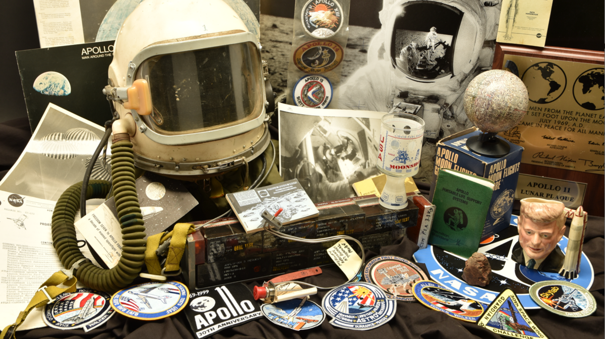 A collection of space memorabilia including Nasa patches, a headset, and numerous knick-knacks