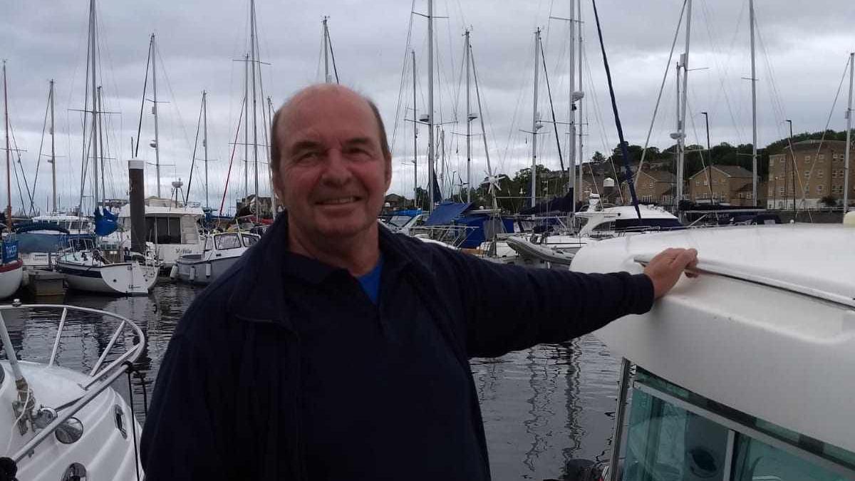 A man stood on a boat looking at the camera